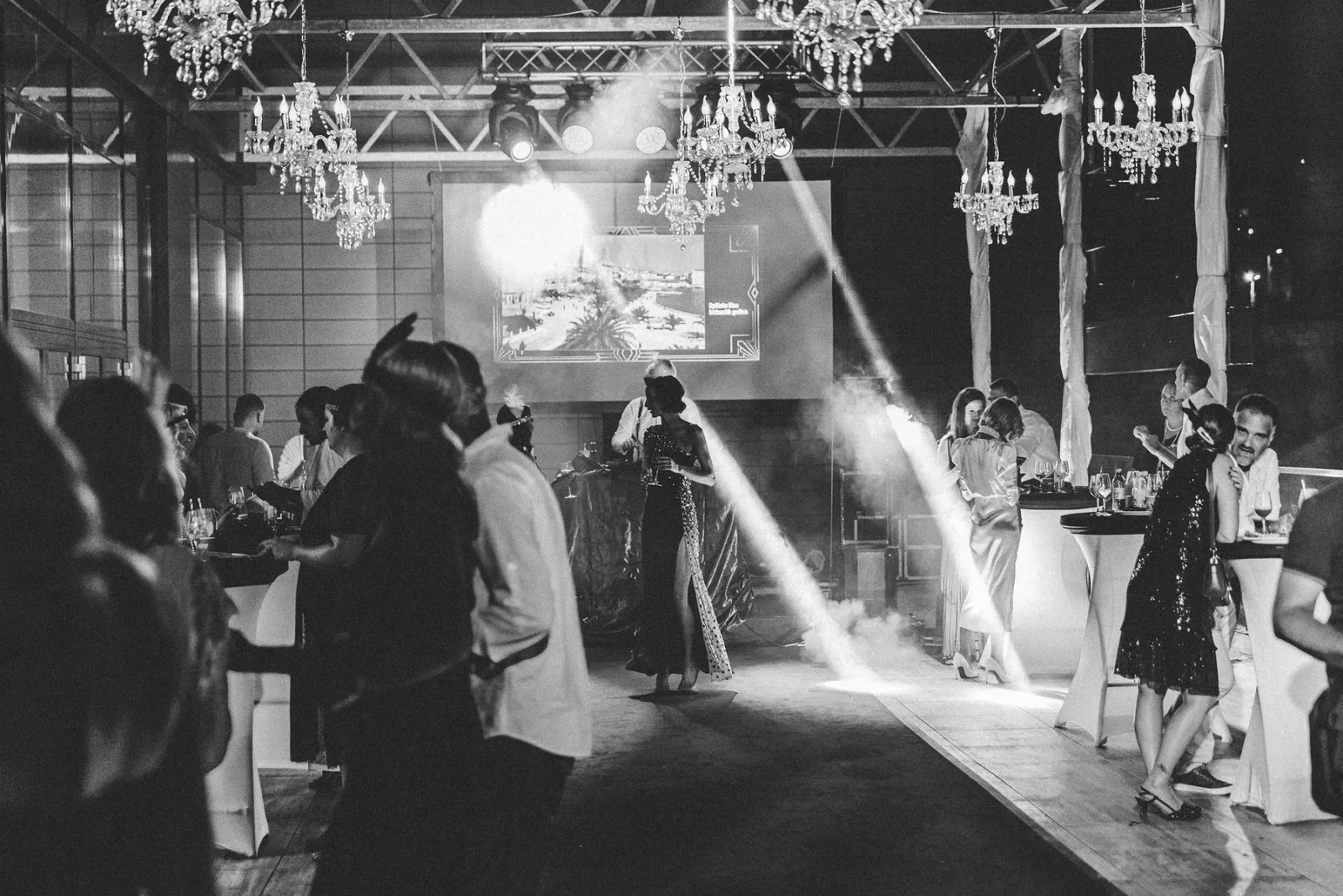 Dentelli Great Gatsby party in black and white with chandeliers, guests, and stage lighting